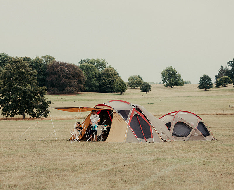 father and daughter sit in their tent in a field