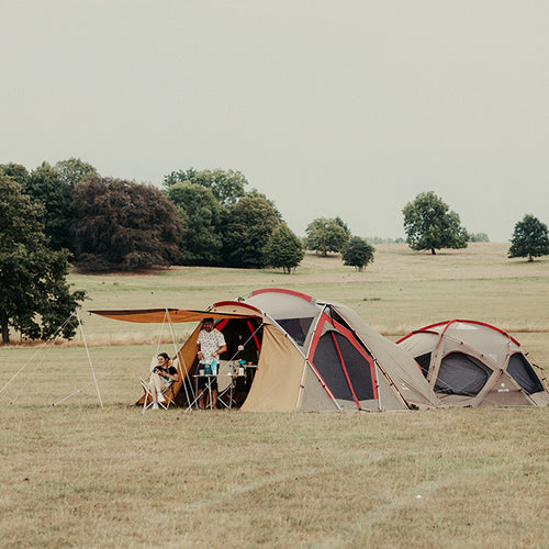 father and daughter sit in their tent in a field
