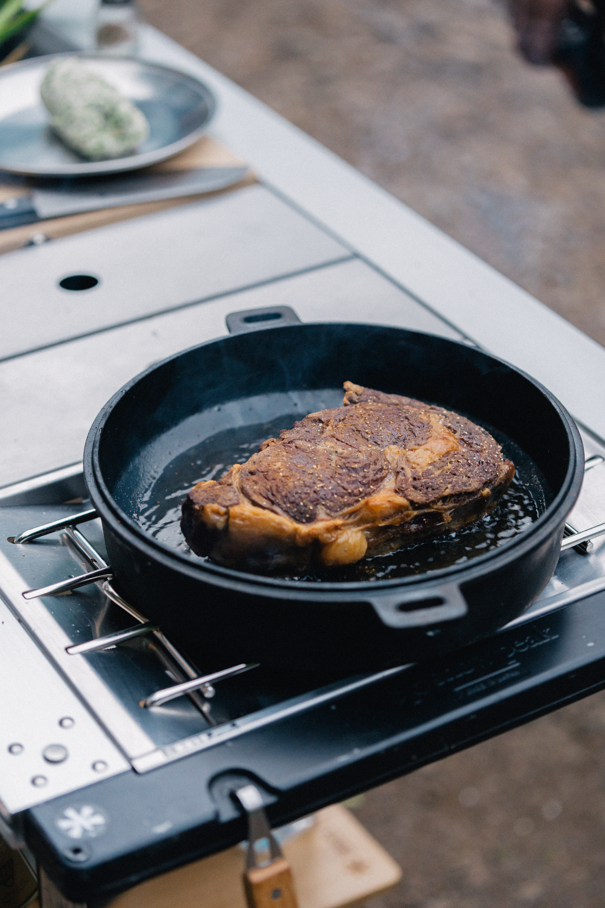 Steak cooking in a cast iron pan on a Snow Peak Flat Burner
